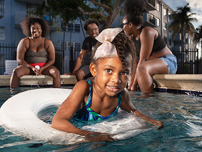 Young girl in middle of pool with older girls looking on